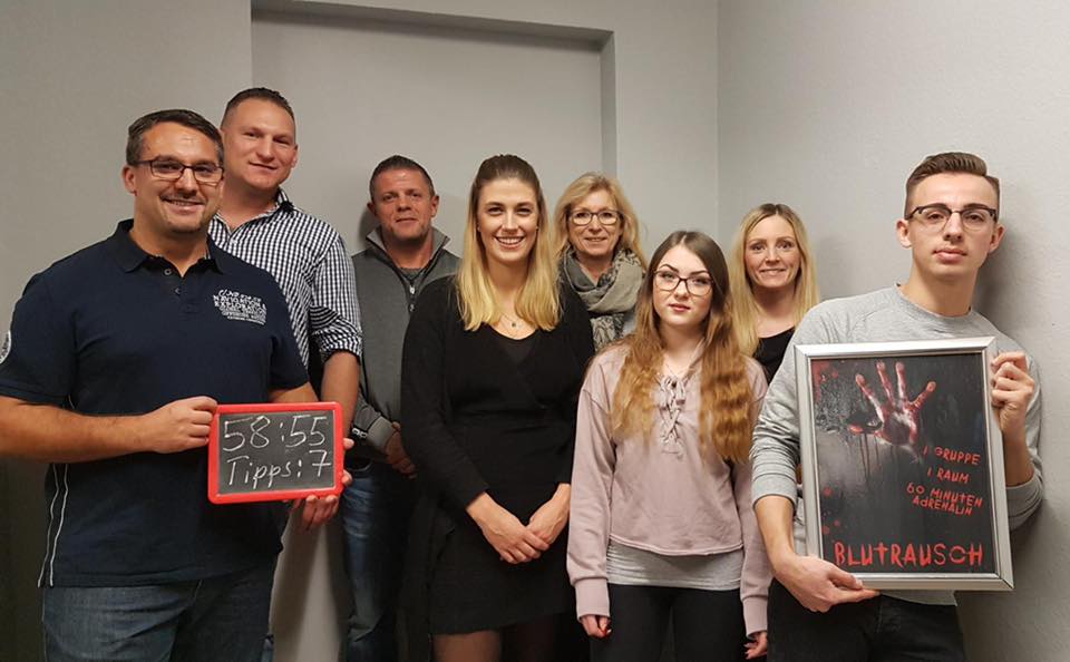 Gruppenfoto von acht Personen; zwei halten ein Tafel- und ein gerahmtes Plakat